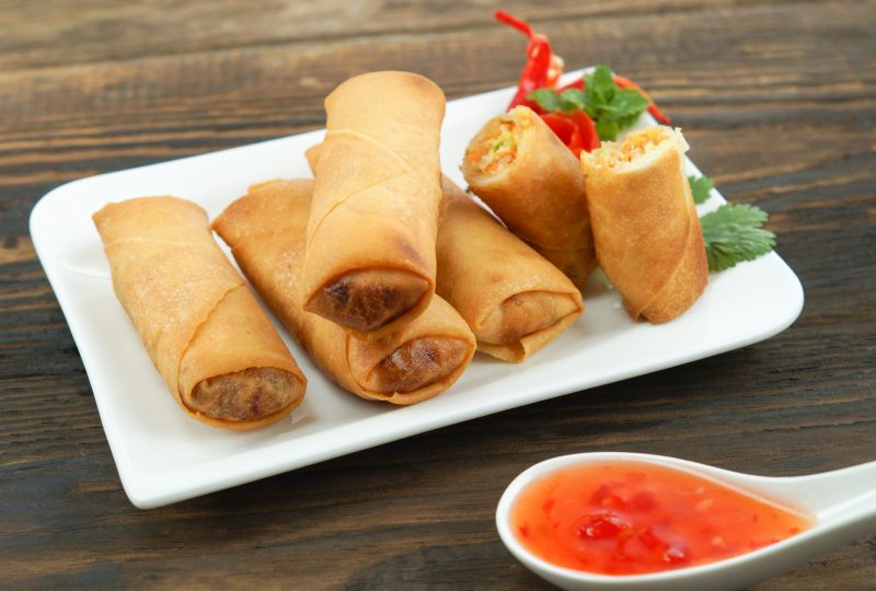 fried-chinese-spring-rolls-served-with-chili-sauce-decorated-rose-tomatoes-with-green-leaved-wood-space-concept-asian-food